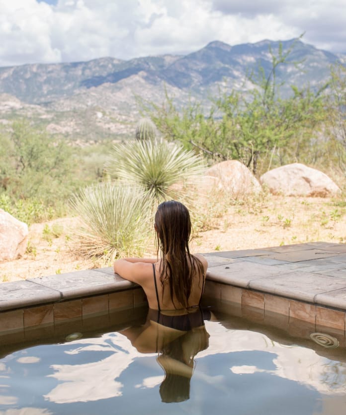 person resting in pool looking at landscape