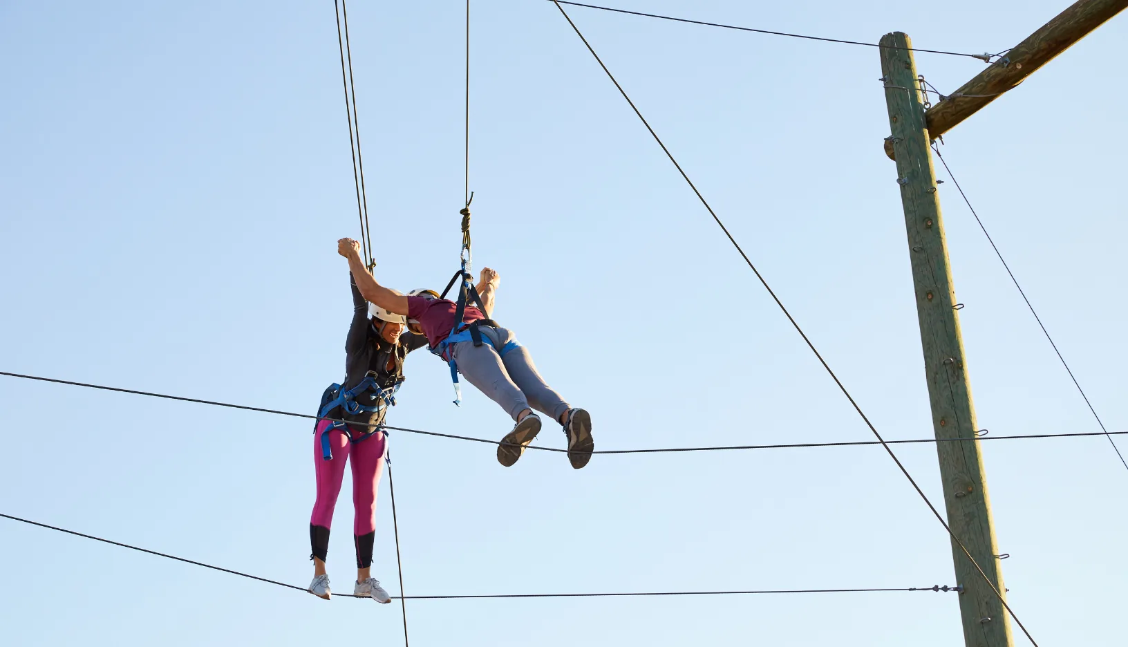 Two participants navigate Miraval Arizona’s Sky Island Traverse Challenge Course during a team retreat.