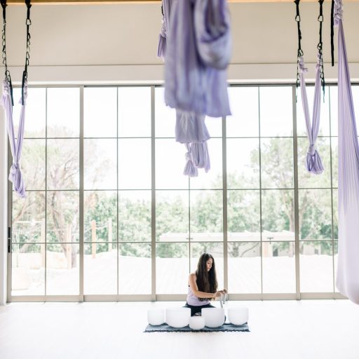 person using sound bowls in aerial yoga room