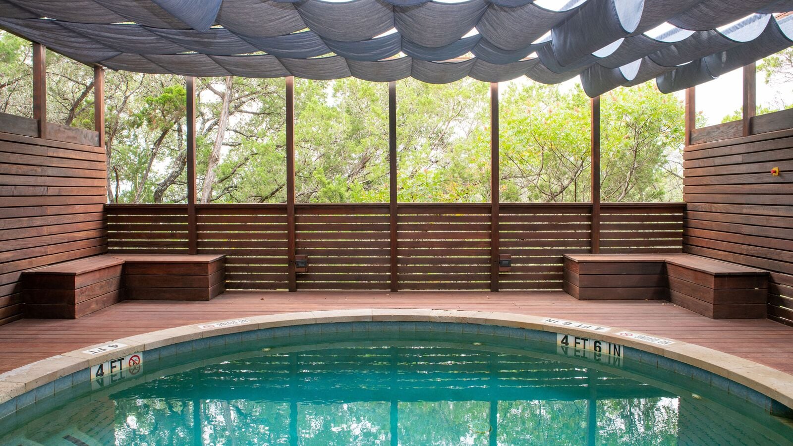 covered pool area with wooden plank walls and seating