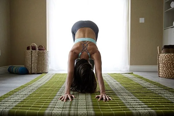 person doing downward dog yoga pose inside