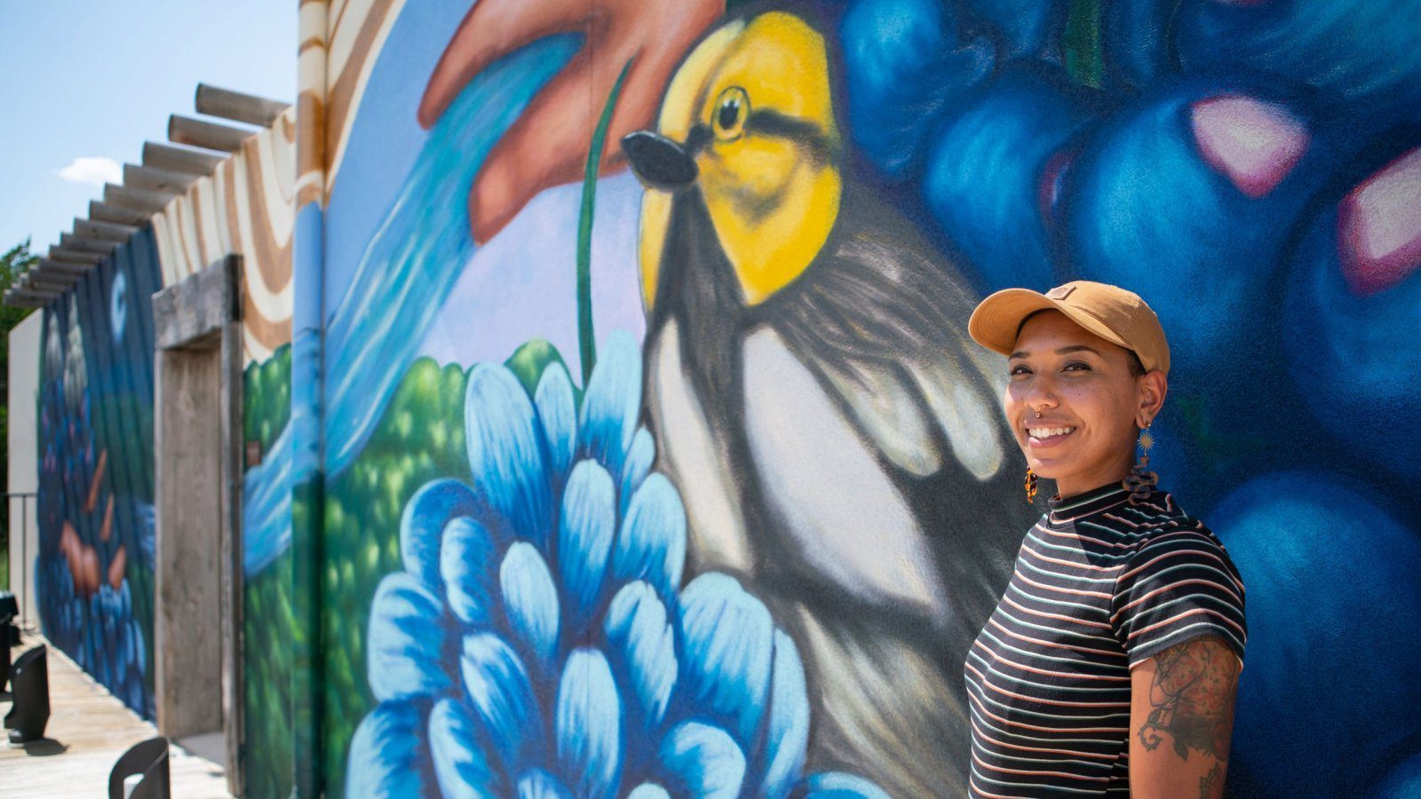 person standing beside mural of bird and flowers