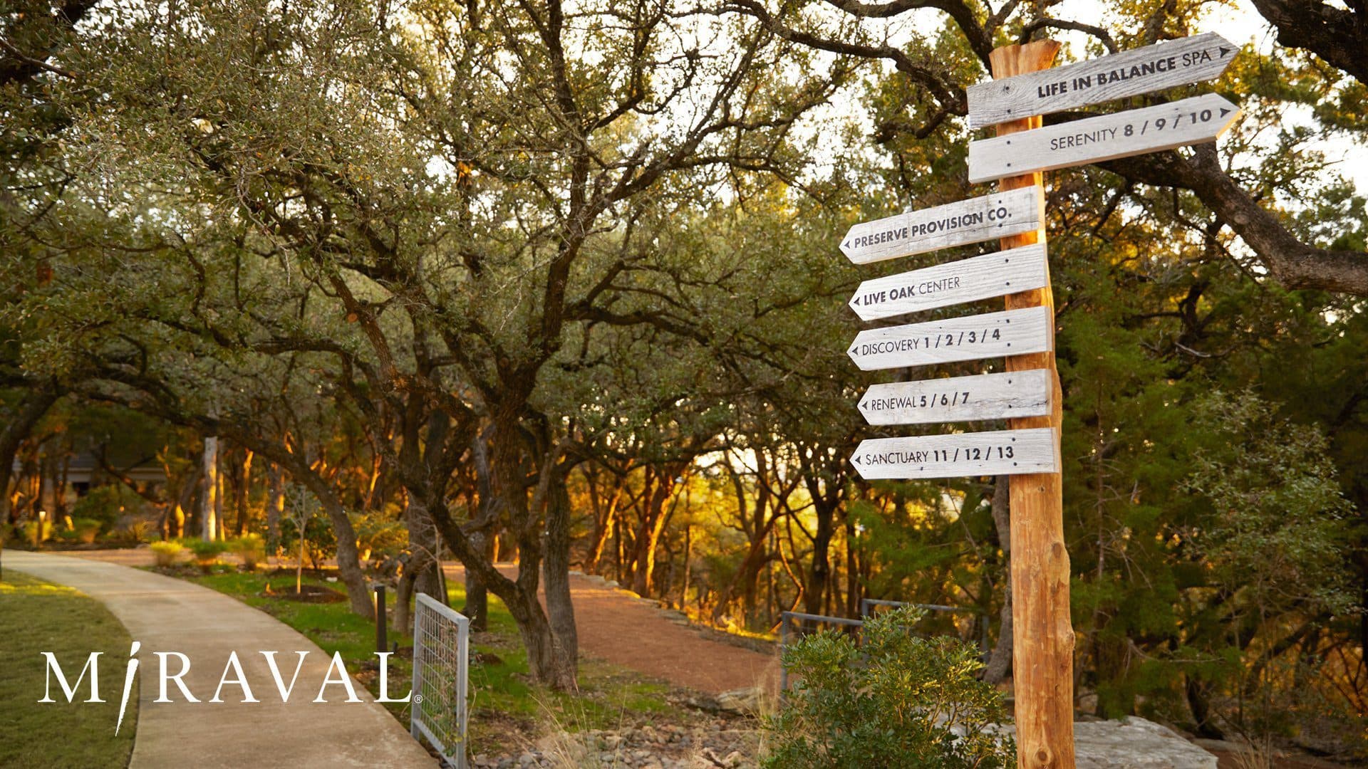 Sign with directions of resort along path with trees