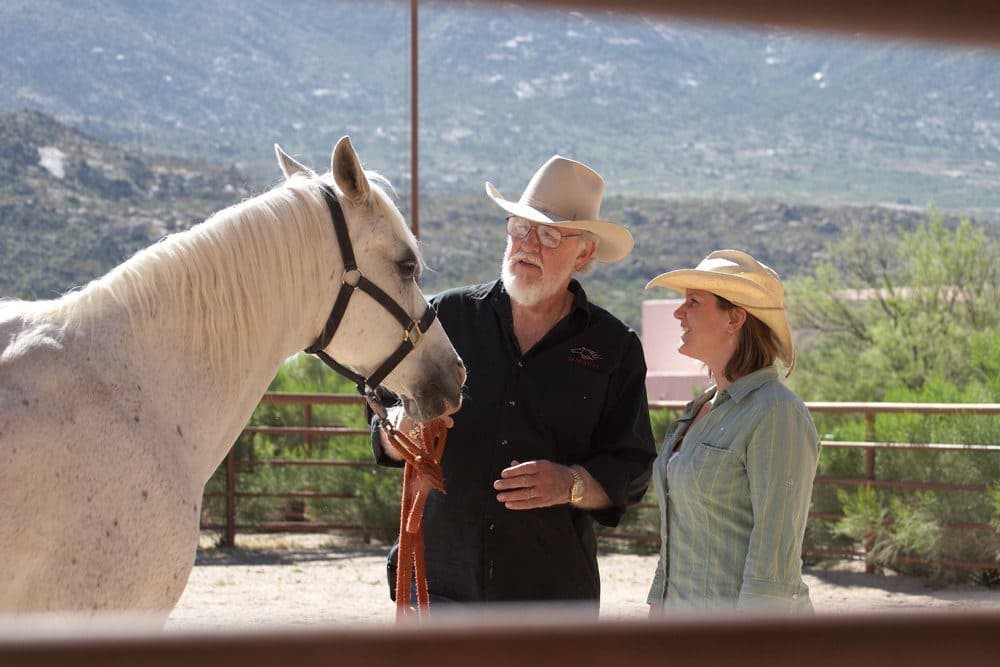 couple standing with a horse outside