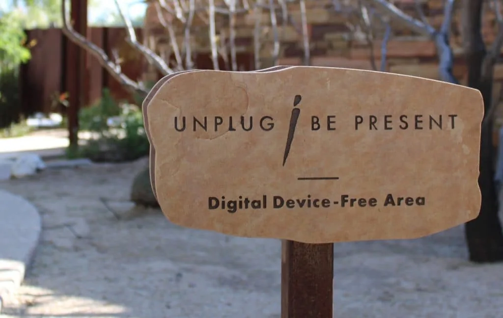 sign that reads unplug be present digital device-free area