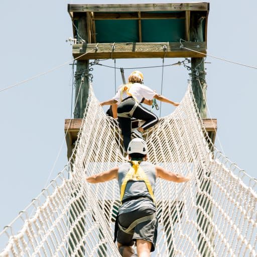 people climbing up a rope bridge