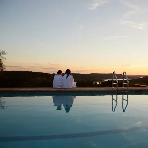 two people watching the sun set by the pool