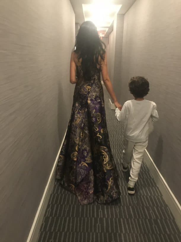 Huma Abedin and son holding hands, walking in hallway