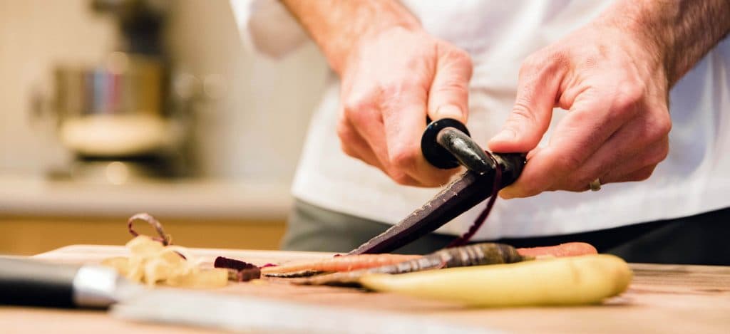 Close up of hands peeling carrots with a peeler