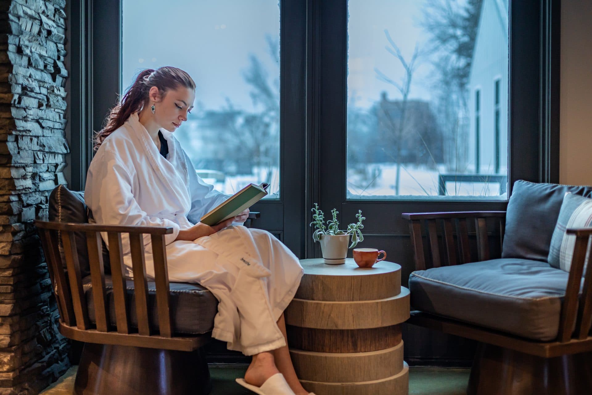 Woman in robe sitting on window reading a book