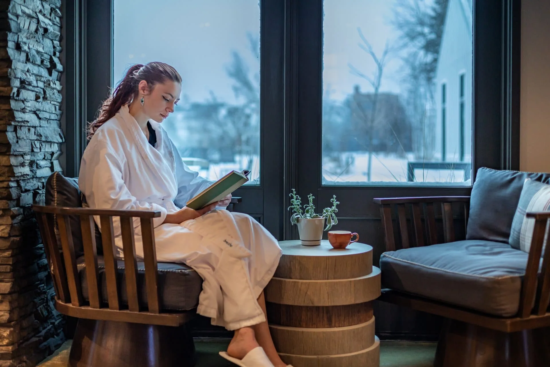 Woman in robe sitting on window reading a book