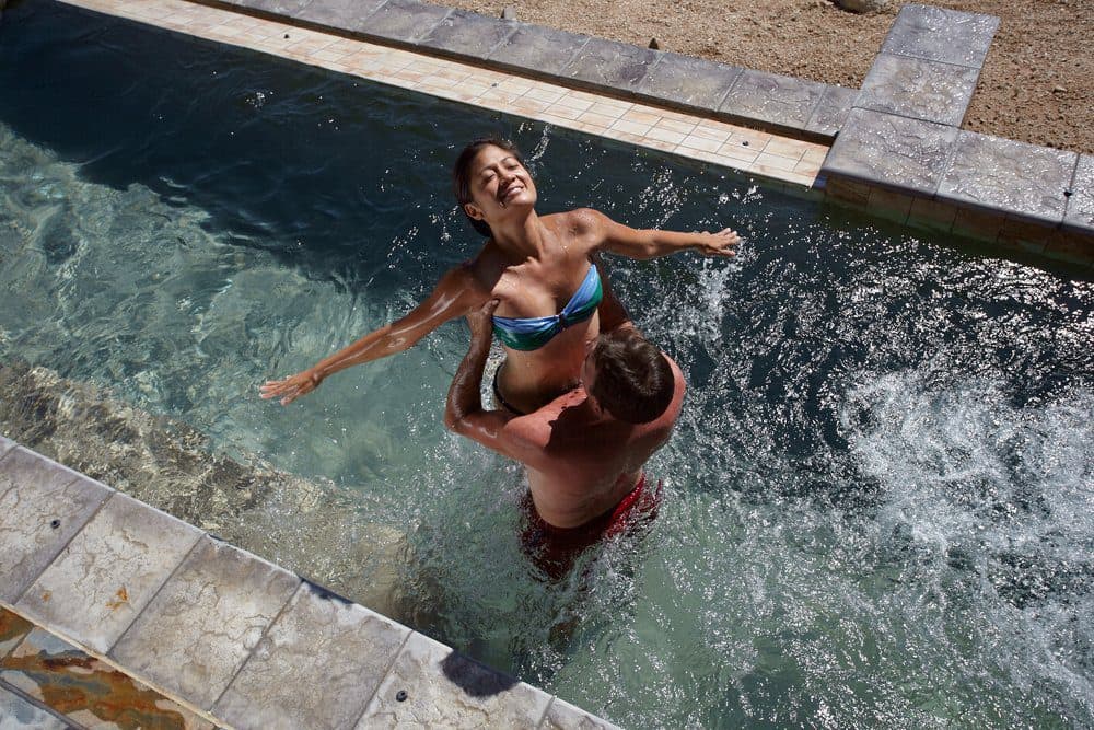 person lifting partner in the air as they stand in pool